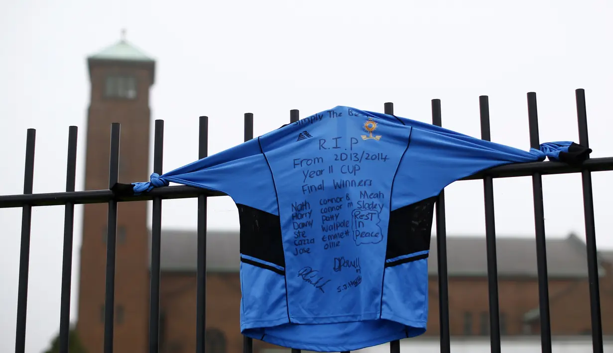 Sebuah kaos olahraga dibentangkan di pagar sekolah oleh para murid yang berduka atas kematian guru bahasa Spanyol mereka, Anne Maguire, Selasa (29/04/2014) (Reuters/Darren Staples).