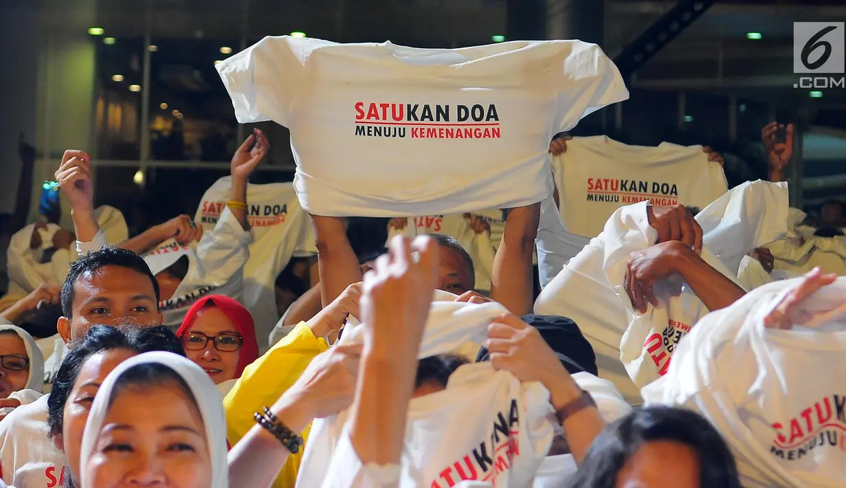 Pendukung Jokowi-Ma'ruf Amin mengangkat kaus pada acara Doa Bersama Lintas Agama dan Festival Seni Budaya di Jakarta, Jumat (12/4). Acara yang digelar Gerakan Alumni UI dan IKJ mengusung tema "SATUkan Doa menuju Kemenangan". (Liputan6.com/Angga Yuniar)