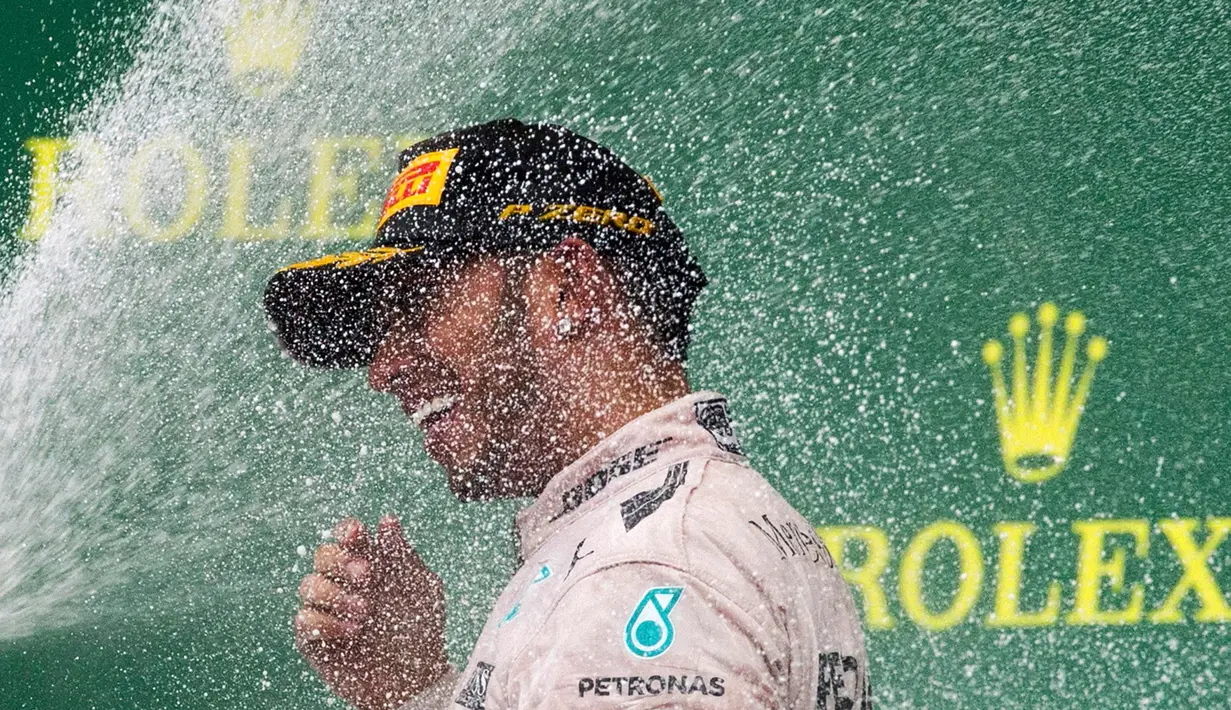 Pembalap Mercedes, Lewis Hamilton disemprot sampanye usai memenangkan GP F1 Amerika Serikat di Sirkuit The Americas, Minggu (25/10). Ini merupakan gelar juara dunia ketiga bagi Hamilton setelah sebelumnya diraih pada 2008 dan 2014. (REUTERS/Adrees Latif)