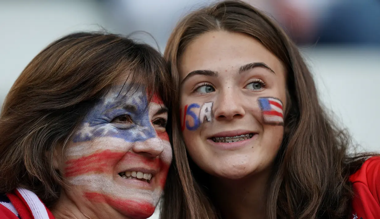 Dua fans wanita AS tersenyum sebelum pertandingan Grup F Piala Dunia Wanita 2019 antara Amerika Serikat melawan Thailand di Stadion Auguste-Delaune di Reims, Prancis (11/6/2019). (AFP Photo/Lionel Bonaventure)