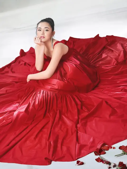 Potret memesona Amanda Manopo yang cantik luar biasa dibalut gaun merah super besar. Ia berpose duduk memamerkan wajahnya yang dirias natural menampilkan kecantikan alami, rambut digulung ke belakang menyisakan beberapa helai kecil sebagai poni yang manis. [Foto: Instagram/harionohalim]