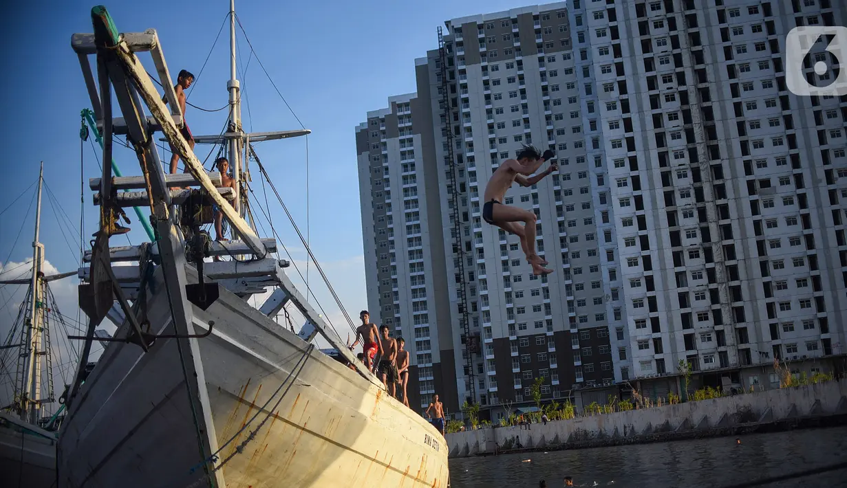 Seorang anak melompat dari atas kapal yang tengah bersandar di Pelabuhan Sunda Kelapa, Jakarta, Senin (6/7/2020). Mereka memanfaatkan waktu libur sekolah dengan bermain lompatan sambil berkumpul bersama teman-teman. (Liputan6.com/Fery Pradolo)