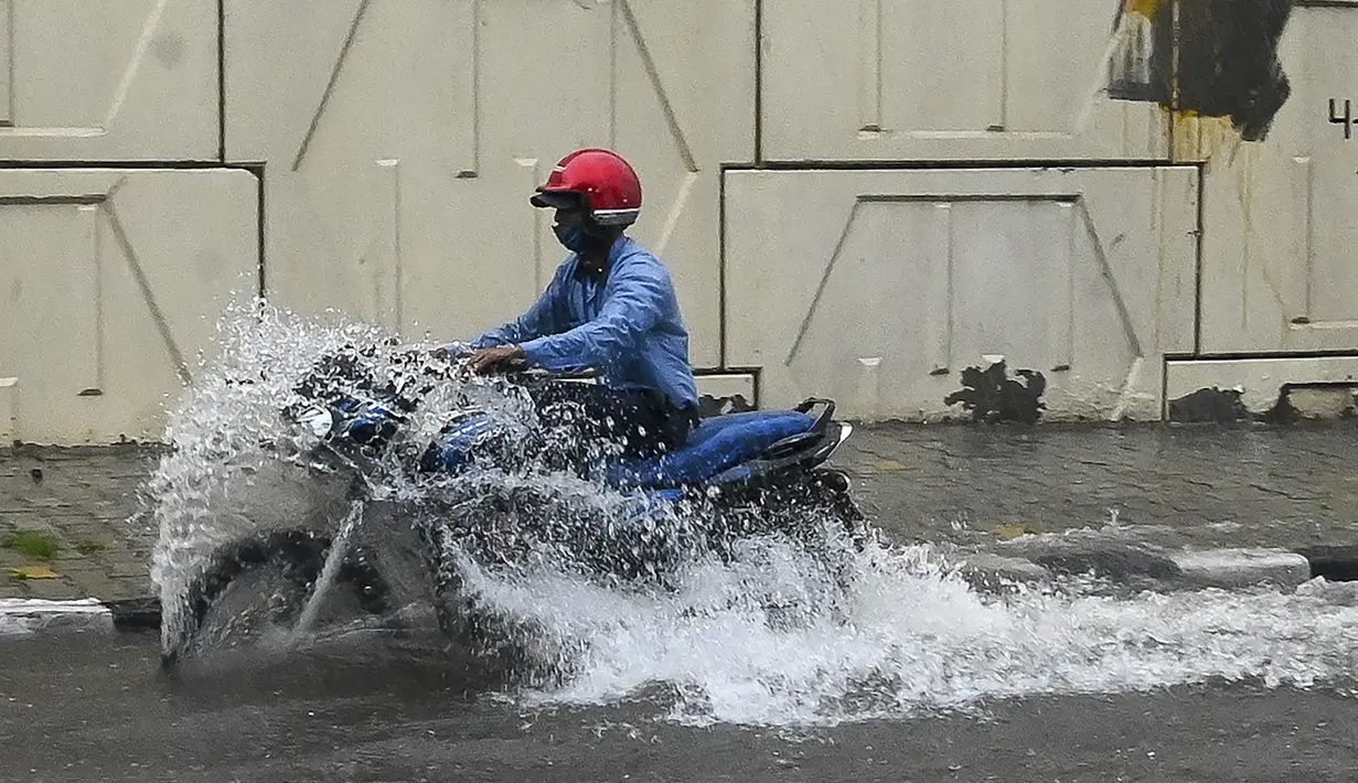 Pengendara motor melewati jalan yang tergenang air saat hujan lebat di New Delhi, India (1/9/2021). Polisi Lalu Lintas Delhi mengeluarkan peringatan yang menginformasikan bahwa ada penghalang lalu lintas di Subway Pasar Azad menuju Pratap Nagar karena genangan air. (AFP/Prakash Singh)