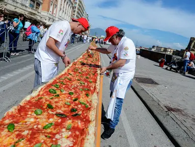 Sejumlah koki ahli berupaya mencetak rekor dunia dengan membuat pizza terpanjang di dunia, di sepanjang pinggir Laut Naples, Italia, 18 Mei 2016. Pizza itu memiliki ukuran sekitar 1 mil dan terbentang di sepanjang pinggir Laut Naples. (Mario LAPORTA/AFP)