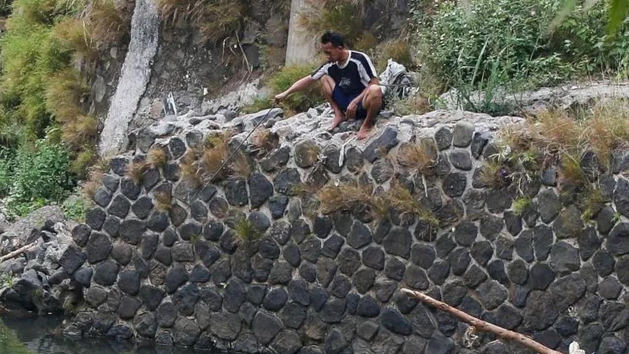 Seorang warga sedang asyik memancing di aliran sungai Ciliwung yang surut saat musim kemarau di kawasan Pulo Geulis Kota Bogor.