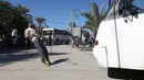 Mohamed Barka, pria yang dijuluki "Super Hero" asal Palestina menarik sebuah bus dengan gigi dalam aksinya di Deir Al-Balah, Gaza Tengah, Kamis (4/2). (MOHAMMED ABED/AFP)