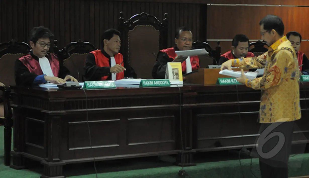 Romi Herton (berdiri) memberikan salinan naskah pembelaan dirinya atas kasus dugaan suap penanganan sengketa pilkada Kota Palembang yang melibatkan Akil Mochtar  di Pengadilan Tipikor, Jakarta, Senin (23/2/2015).  (Liputan6.com/Herman Zakharia)