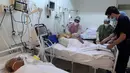 Petugas medis Tunisia merawat pasien di gym yang diubah untuk menangani lonjakan infeksi COVID-19 di pusat kota Kairouan pada 4 Juli 2021. Tunisia tengah berjuang menghadapi tsunami COVID-19 sementara jumlah orang yang meninggal akibat virus corona terus melonjak tinggi. (FETHI BELAID/AFP)