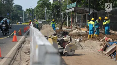 Pekerja menyelesaikan pembangunan pedestrian di Jalan Lapangan Banteng, Jakarta, Minggu (16/7). Pemprov DKI Jakarta menargetkan dapat membangun pedestrian sepanjang 45 kilometer per tahun. (Liputan6.com/Helmi Afandi)