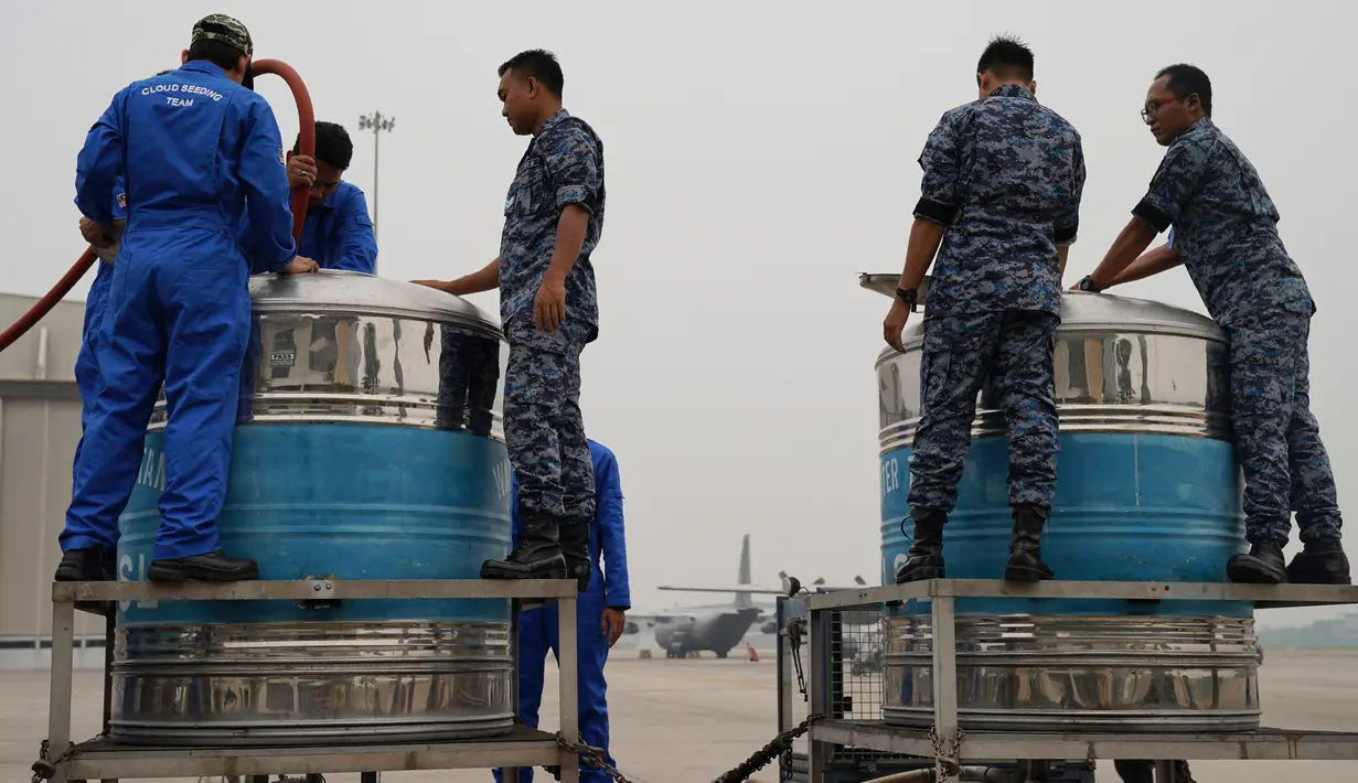 Tim penyemaian awan bersama prajurit Angkatan Udara menyiapkan tangki berisi larutan air garam di Pangkalan Udara Militer Subang, Malaysia, Kamis (19/9/2019). Malaysia melakukan operasi penyemaian awan untuk mendorong hujan dalam mengatasi kabut asap yang melanda. (AP Photo/Vincent Thian)