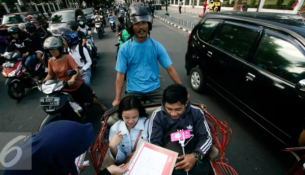 Komunitas Gerakan Literasi Aksara Jawa membagikan kalender berhuruf Jawa kepada  pengunjung  pada peringatan Hari Aksara Internasional ke-50 di Titik Nol km, Yogyakarta, Kamis (8/9). (Liputan6.com/ Boy Harjanto)