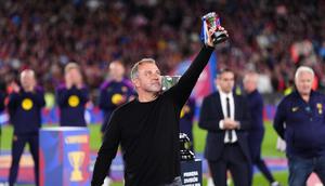 Pelatih kepala Barcelona, Hansi Flick, mengangkat trofinya ke langit sambil merayakan kemenangan setelah mengalahkan Real Madrid 2-0 untuk menjuarai liga sepak bola Spanyol (La Liga) dengan tiga pertandingan tersisa, di Barcelona, Spanyol, Minggu, 10 Mei 2026. (AP Photo/Joan Mateu Parra)
