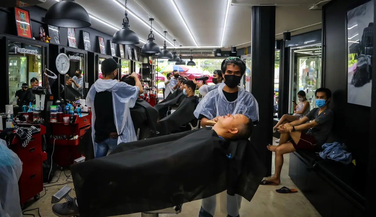 Penata rambut melayani pelanggan di sebuah salon yang dibuka kembali saat pelonggaran beberapa langkah pengendalian karena Virus Corona COVID-19 di Bangkok, Minggu (3/5/2020). Pemerintah Thailand mulai melonggarkan aturan pembatasan pergerakan orang dan pertemuan. (VIVEK PRAKASH/AFP)