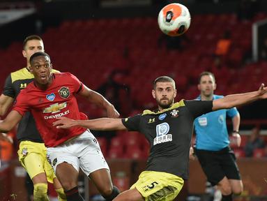 Striker Manchester United, Anthony Martial, berebut bola dengan pemain Southampton pada laga lanjutan Premier League pekan ke-35 di Stadion Old Trafford, Selasa (14/7/2020) dini hari WIB. Manchester United bermain imbang 2-2 atas Southampton. (AFP/Peter Powel/pool)