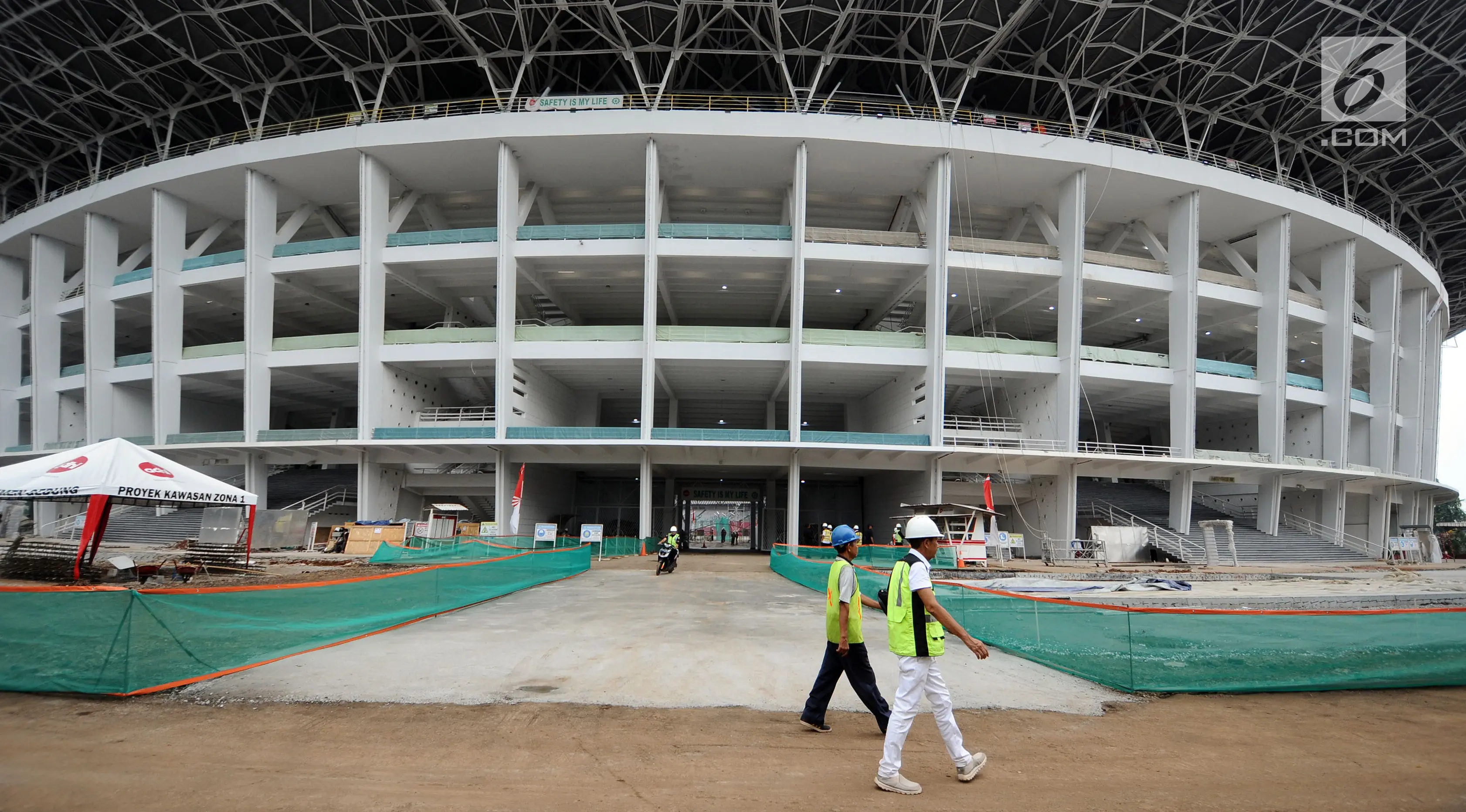 Pekerja melintas di area renovasi Stadion Utama GBK, Jakarta, Selasa (3/10). Sejumlah pembangunan Infastruktur Asian Games dipastikan akan selesai sesuai dengan target pemerintah, yaitu akhir tahun 2017. (Liputan6.com/Helmi Fithriansyah)