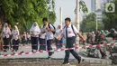 Pelajar melintasi trotoar yang sedang direvitalisasi di kawasan Kramat Raya, Jakarta, Rabu (6/11/2019). Revitalisasi trotoar menyebabkan para pejalan kaki harus berjalan di pinggir jalan dan bersinggungan dengan sepeda motor. (Liputan6.com/Faizal Fanani)