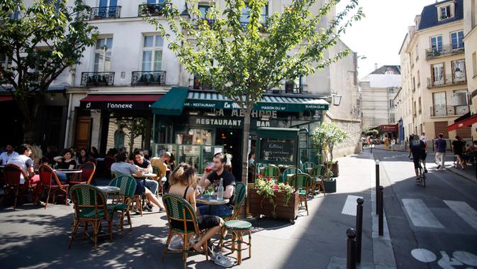 Orang-orang duduk di teras kafe di Paris, Selasa (2/6/2020). Warga Paris terkurung selama berbulan-bulan karena lockdown Corona namun, kini sebagian kafe dan restoran di kota itu dibuka kembali usai pelonggaran pembatasan. (AP Photo/Christophe Ena)