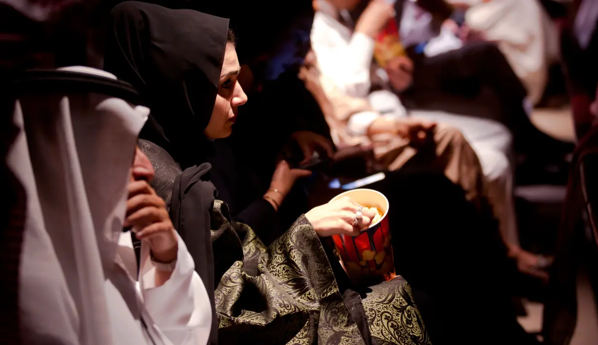 Tamu undangan memakan popcorn saat menghadiri acara gala undangan di King Abdullah Financial District Theatre, ibu kota Riyadh, Rabu (18/4). Setelah pelarangan selama 35 tahun, bioskop kembali beroperasi di Arab Saudi. (AP/Amr Nabil)