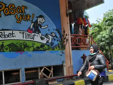 Pengunjung melintas di dekat lukisan mural di Pasar PSPT, Tebet, Jakarta (14/11/2015). Keberadaan seni mural di pasar ini bisa membuat pengunjung tersenyum. (Liputan6.com/ Gempur M Surya)