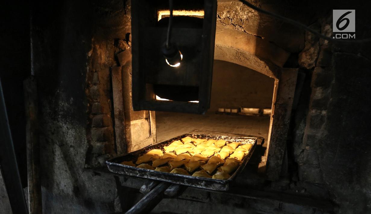 Karyawan memanggang roti dengan kayu bakar ke dalam tungku di Toko Roti GO, Purwokerto, Jawa Tengah, Senin (22/4). Memasuki usia ke 121 tahun, toko roti yang berdiri sejak tahun 1898 ini dibuat mengunakan peralatan tradisional dan tanpa bahan pengawet. (Liputan6.com/Fery Pradolo)