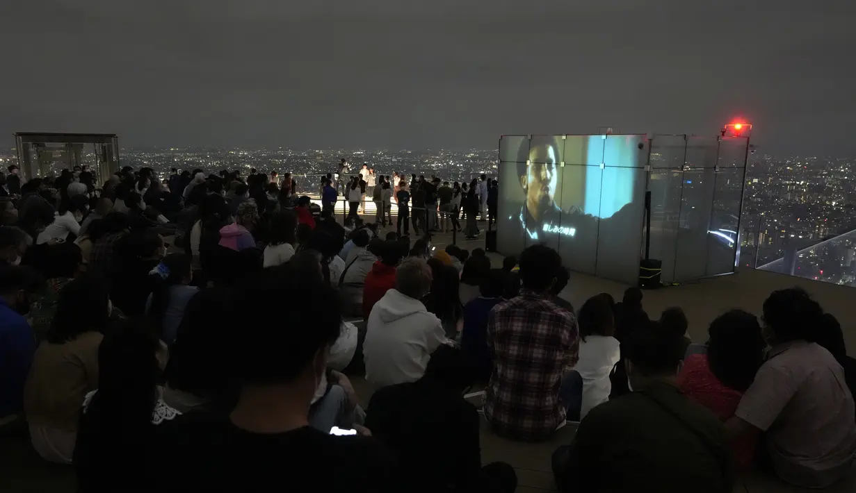Pengunjung menonton film di rooftop dek observasi Shibuya Sky di Tokyo, Sabtu (9/10/2021). seminggu setelah Jepang sepenuhnya keluar dari keadaan darurat virus corona untuk pertama kalinya dalam lebih dari enam bulan. (AP Photo / Kiichiro Sato)