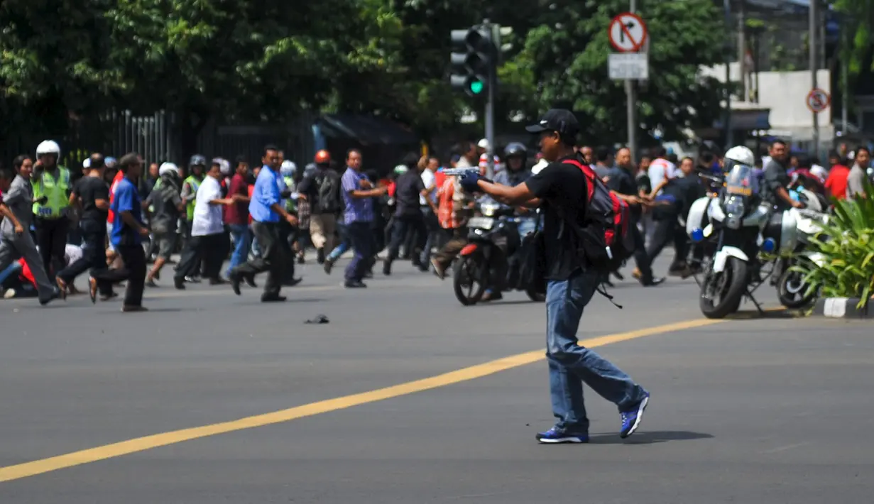 Di tengah kepanikan pasca ledakan di Jalan Thamrin, Jakarta, seorang pria yang diperkirakan berusia antara 20-30 tahun, berpakaian kaos dan bertopi hitam serta membawa ransel merah, tiba-tiba mengeluarkan senjata, Kamis (14/1). (REUTERS/Veri Sanovri/Xin)