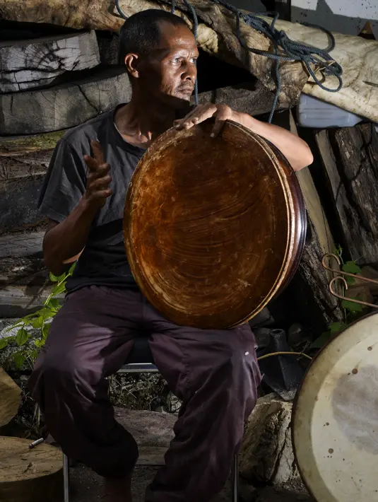Pembuat rebana tradisional, Fajar Siddiq, yang kehilangan pekerjaan karena pandemi Covid-19, beristirahat di rumahnya di Lambaro, Provinsi Aceh, Senin (22/2/2021). Usaha produksi berbagai jenis alat musik tradisional Aceh berupa rapai, serune kale dan seruling mulai langka (CHAIDEER MAHYUDDIN / AFP)