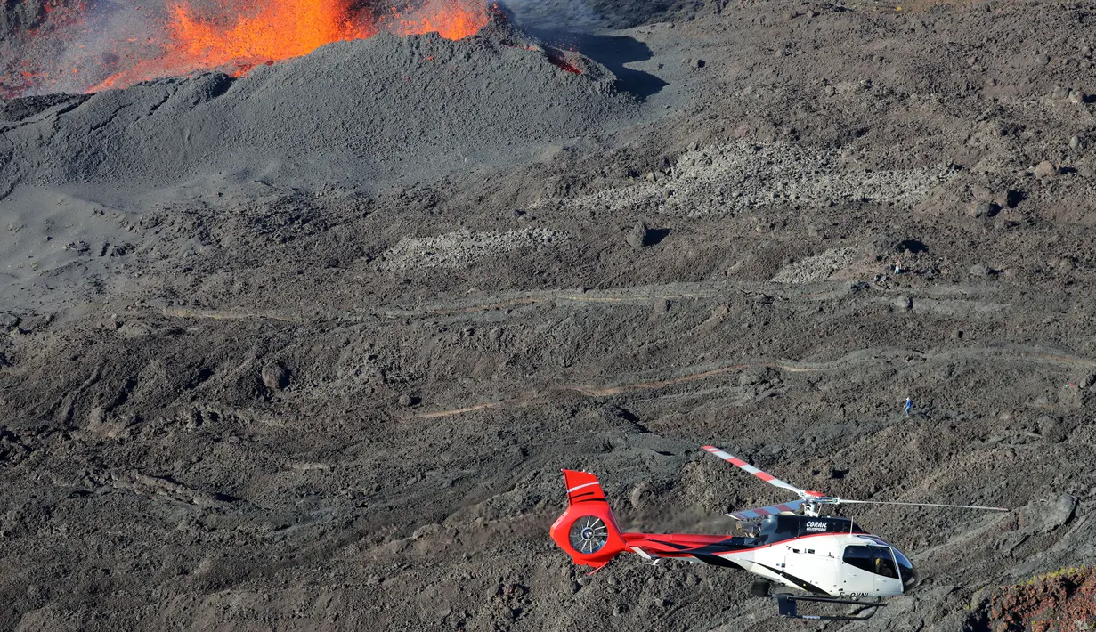 Sebuah helikopter terbang di dekat puncak Gunung Piton de la Fournaise, Prancis, Rabi (1/2). Gunung tersebut kembali meletus pada Selasa (31/1) malam waktu setempat dan terus menyemburkan lava pijar. (AFP Photo/Richard Bouhet)