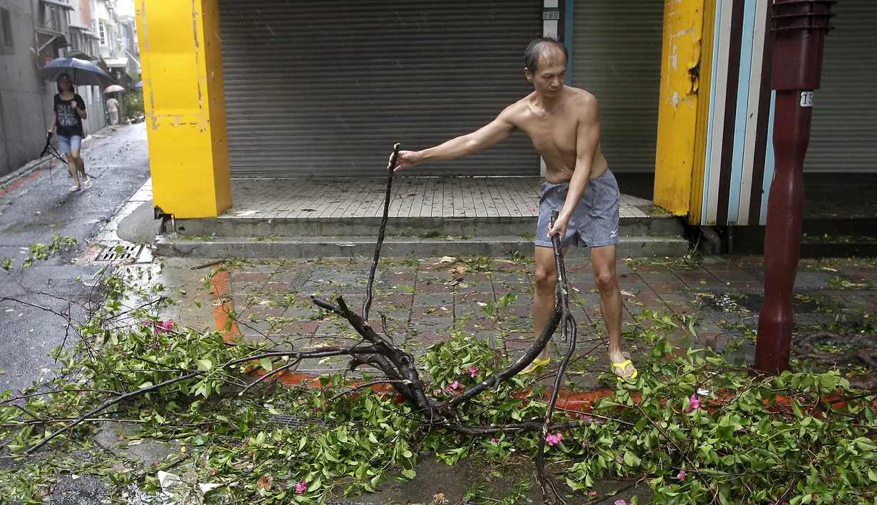 Seorang pria membersihkan pohon pohon yang tumbang di dekat rumahnya usai angin kencang Topan Soudelor di Taipei, Taiwan, (8/8/2015). Empat orang tewas akibat peristiwa angin kencang Topan Soudelor dan hujan deras.  (REUTERS/Pichi Chuang)