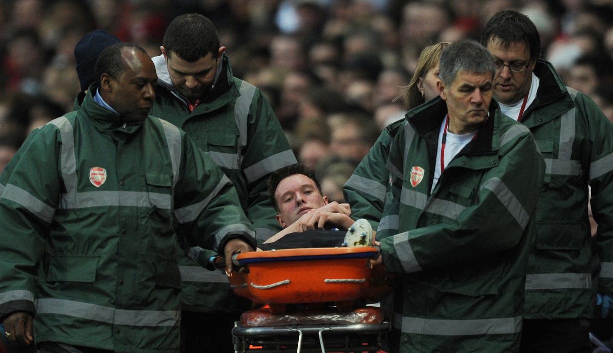 Pemain Manchester United, Phil Jones (tengah), ditandu keluar lapangan setelah mengalami cedera dalam pertandingan lanjutan Liga Inggris 2011/2012 melawan Arsenal yang berlangsung di Emirates Stadium(22/1/2012). Badai cedera berkepanjangan belakangan ini membuat Jones minim menit bermain dan alasan utama ia hengkang dari MUdi akhir musim 2022/2023 ini. (AFP/Adrian Dennis)