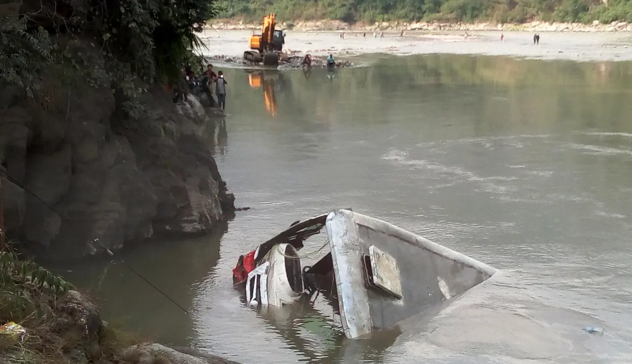 Sebuah bus sarat penumpang keluar dari jalan raya dan tercebur ke dalam sungai Trishuli di Distrik Dhading, Nepal Tengah, Sabtu (28/10). Sedikitnya 31 orang tewas, termasuk 11 anak-anak, dan belasan lainnya menderita luka. (HARIHAR SINGH RATHOR/AFP)