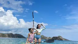 Pose kompak kece Tyna Dwi Jayanti di atas perahu warna biru bersama putrinya, Aluna Mirdad. Tyna mengenakan long sleeve bikini bernuansa biru. Untuk bawahan bikini memiliki model high waist yang memberi kesan sporty. (Instagram/tynadwijayanti)