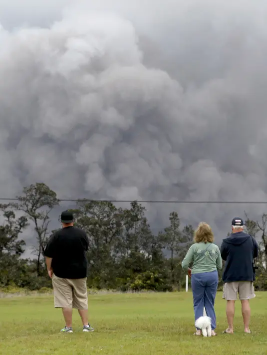 Wisatawan menyaksikan asap tebal yang berembus dari puncak gunung berapi Kilauea di Hawaii. Kamis (17/5). Para wisatawan tetap santai dan justru menjadikan letusan gunung ini sebagai objek wisata. (AP Photo/Caleb Jones)