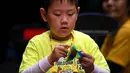 Seorang anak semangat memecahkan permainan rubik pada kejuaraan kubus Rubik Dunia di Melbourne, Australia (12/7/2019). Kejuaraan Dunia diadakan setiap dua tahun dan telah menarik 905 pesaing dari seluruh dunia yang bersaing dalam 18 acara yang berbeda. (AFP Photo/William West)