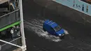 Seorang wanita melihat van melintasi banjir saat hujan lebat di distrik The Nine Elms London (25/7/2021). Bus dan mobil terjebak banjir ketika jalan-jalan di London banjir pada hari Minggu, ketika badai petir berulang kali melanda ibu kota Inggris. (AFP/Justin Tallis)