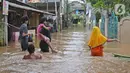 Warga menorobos banjir yang merendam kawasan Cipinang Melayu, Jakarta Timur, Jumat (19/2/2021). Banjir di kawasan tersebut akibat curah hujan yang tinggi dan meluapnya air dari Kali Sunter. (Liputan6.com/Herman Zakharia)