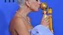 Lady Gaga mencium piala penghargaan Golden Globes 2019 di The Beverly Hilton, California, Minggu (6/1). Lagu Lady Gaga berjudul 'Shallow' memenangkan Golden Globes 2019 kategori lagu orisinal terbaik. (KEVIN WINTER/GETTY IMAGES NORTH AMERICA/AFP)