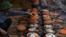 Seorang pria memasak ikan di pot tanah liat menggunakan kayu bakar di provinsi Ha Nam, Vietnam, Selasa (21/1/2020). Makanan lezat populer untuk Tahun Baru Imlek atau Tet di utara Vietnam itu dijual dengan masing-masing pot sekitar Rp 25ribu hingga Rp 80ribu. (Nhac NGUYEN / AFP)