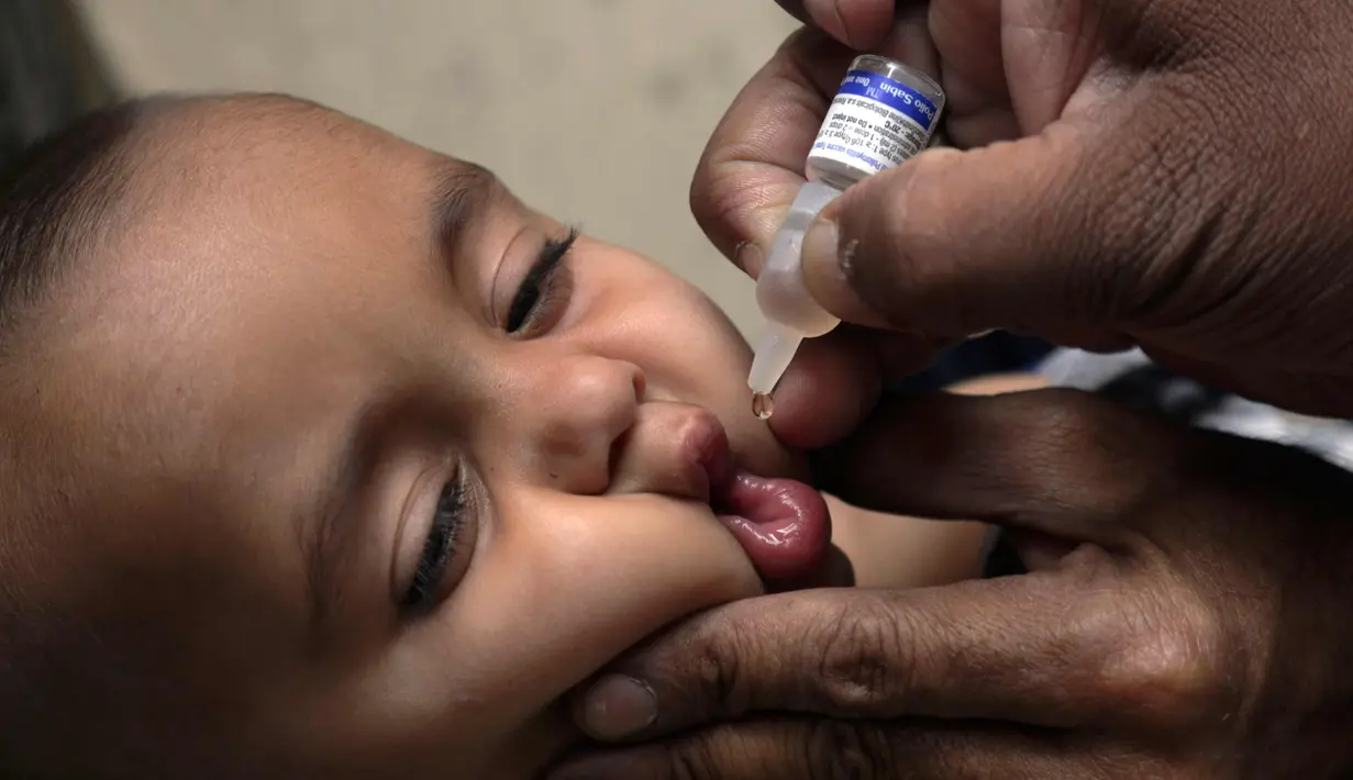 Ekspresi seorang anak saat diberikan vaksin polio oleh pekerja kesehatan di Lahore, Pakistan, (9/4). Pakistan meluncurkan vaksinasi polio baru, yang bertujuan agar 38,7 juta anak di bawah usia 5 tahun mendapatkan vaksin tersebut. (AP Photo/KM Chaudary)