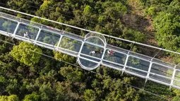 Foto yang diambil pada 4 Mei 2019 menunjukkan orang-orang mengunjungi jembatan berlantai kaca di Huaxi Adventure Park, Provinsi Jiangsu timur China. Jembatan kaca setinggi 518 meter ini menjadi tujuan wisata favorit di China. (Photo by STR / AFP)