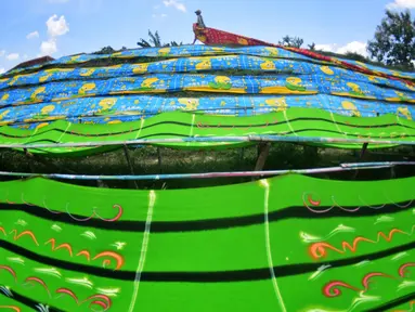 Warga menjemur kain pantai di bantaran sungai di Desa Mojolaban , Kabupaten Sukoharjo, Jawa Tengah, Rabu (25/10). Setiap rumah di desa ini memiliki usaha kain pantai tersebut, mulai dari penyablon hingga penjemurnya. (Liputan6.com/Gholib)