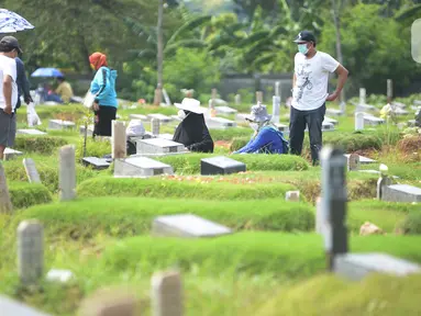 Warga berdoa saat melakukan ziarah di area pemakaman khusus COVID-19 di TPU Rorotan, Cilincing, Jakarta Utara, Rabu (4/5/2022). Sejumlah tempat pemakaman umum masih dipadati oleh keluarga yang melakukan ziarah di H+3 Lebaran. (merdeka.com/Imam Buhori)