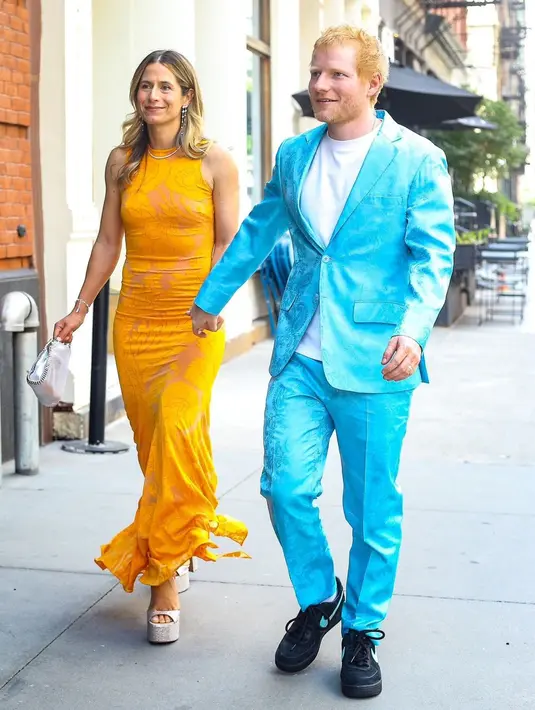 Berbeda dari tamu pria lain yang memilih setelan klasik, Ed Sheeran justru tampil playful mengenakan jas dan celana bermotif paisley berwarna biru elektrik. Ia memadukannya dengan kaus putih polos dan sneakers hitam, menciptakan gaya semi-formal yang santai namun tetap mencolok. Di sampingnya, sang istri tampil anggun dalam gaun fitted warna mustard dengan motif floral samar dan platform heels bernuansa silver.
Berbeda dari tamu pria lain yang memilih setelan klasik, Ed Sheeran justru tampil playful mengenakan jas dan celana bermotif paisley berwarna biru elektrik. Ia memadukannya dengan kaus putih polos dan sneakers hitam, menciptakan gaya semi-formal yang santai namun tetap mencolok. Di sampingnya, sang istri tampil anggun dalam gaun fitted warna mustard dengan motif floral samar dan platform heels bernuansa silver.