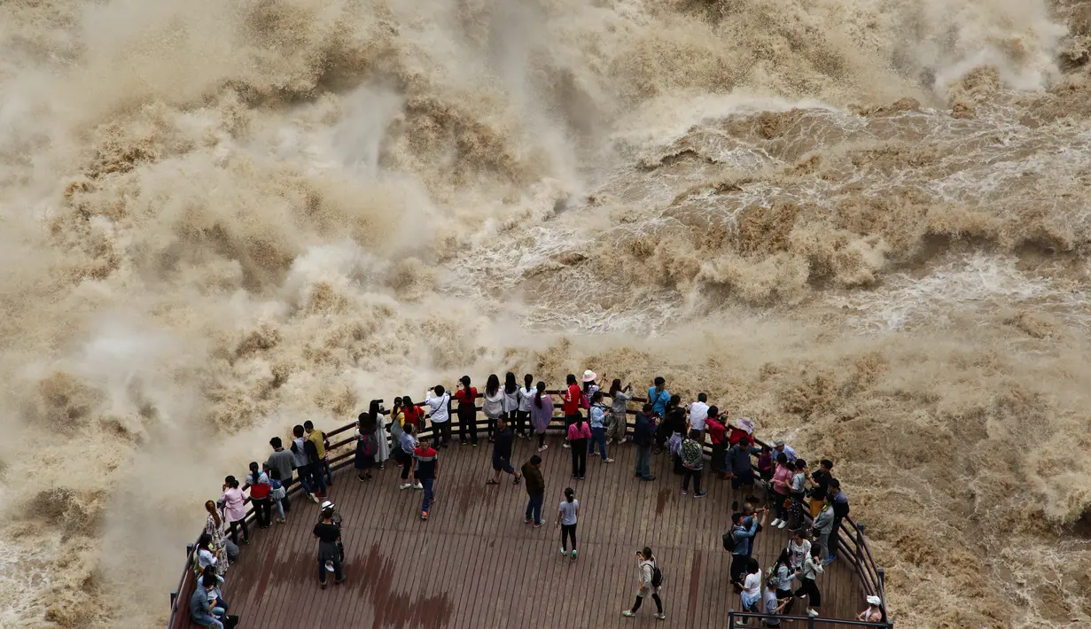 Wisatawan menikmati pemandangan mengerikan derasnya arus sungai Jinsha dari tempat wisata Tiger Leaping Gorge di Diqing, Provinsi Yunnan, China (15/7). (REUTERS / Stringer)