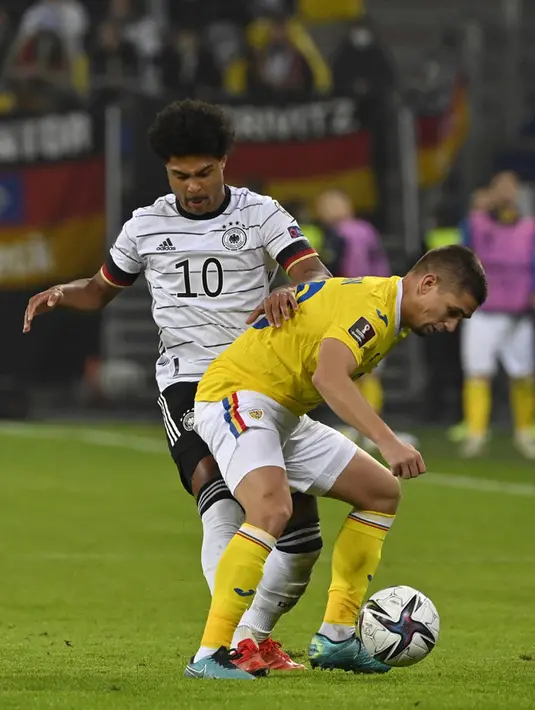 Pemain Jerman Serge Gnabry (kiri) berebut bola dengan pemain Rumania Razvan Marin pada pertandingan Grup J kualifikasi Piala Dunia Qatar 2022 di Hamburg, Jerman, 8 Oktober 2021. Jerman menang 2-1. (John MACDOUGALL/AFP)