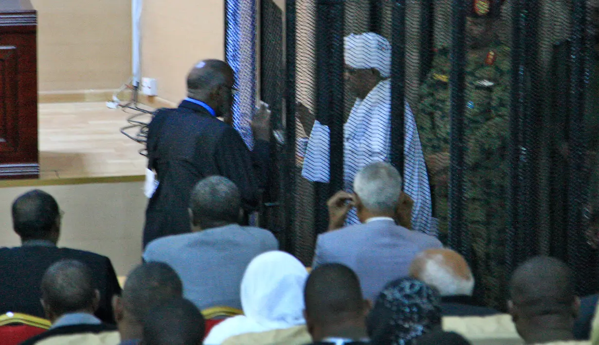 Presiden terguling Sudan, Omar al-Bashir ditempatkan di kandang terdakwa selama menjalani persidangan atas dakwaan korupsi di pengadilan di Khartoum, Senin (19/8/2019). Bashir  didakwa dengan tuduhan korupsi, kepemilikan mata uang asing dan menerima gratifikasi. (Ebrahim HAMID / AFP)