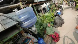 Warga duduk di bawah talang air kawasan Kampung Kamal Muara, Jakarta, Selasa (9/7/2019). Saat musim kemarau, warga Kampung Kamal Muara harus membeli air seharga Rp 5.000 per jeriken untuk kebutuhan mandi, cuci pakaian dan lain-lain. (Liputan6.com/Herman Zakharia)