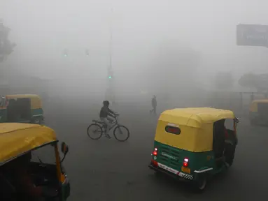 Pengendara sepeda melewati perlintasan di tengah kabut akibat suhu dingin di New Delhi, Senin (30/12/2019). New Delhi, ibu kota India, saat ini mengalami musim dingin dengan hari dingin terpanjang dalam 22 tahun terakhir. (AP Photo/Manish Swarup)