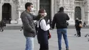 Suami istri mengenakan masker wajah berjalan-jalan di pusat kota Duomo, Milan, Italia, Kamis (27/2/2020). Pemerintah Italia akan melarang orang berciuman di tempat umum, berjabatan tangan dan menjaga jarak yang aman dari masing-masing lain untuk membatasi penyebaran virus corona. (AP Photo/Luca Brun