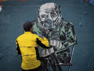 Kevin Belyk melukis mural foto Senator AS Bernie Sanders yang memakai jaket musim dingin dan sarung tangan serta masker wajah pada pelantikan Presiden Joe Biden di taman skateboard Terowongan Leeside di Vancouver, British Columbia (28/1/2021). (Darryl Dyck/The Canadian Press via AP)